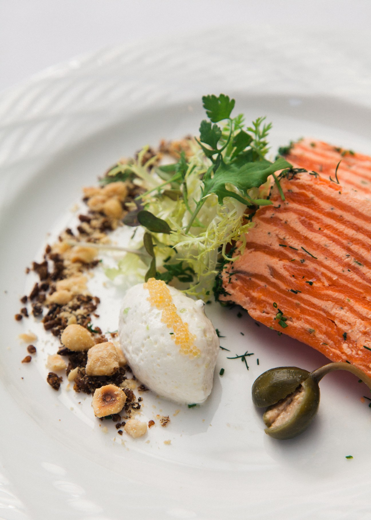 Plated salmon dish with microgreens, white sauce, and garnish at Blue Water Café.