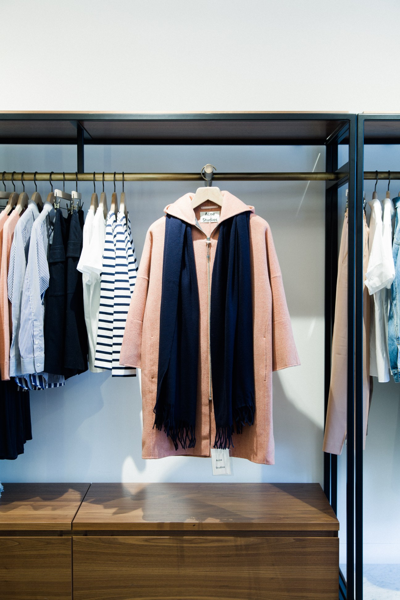 Want Apothecary storefront displaying Acne Studios clothing on brass rails with marble flooring.