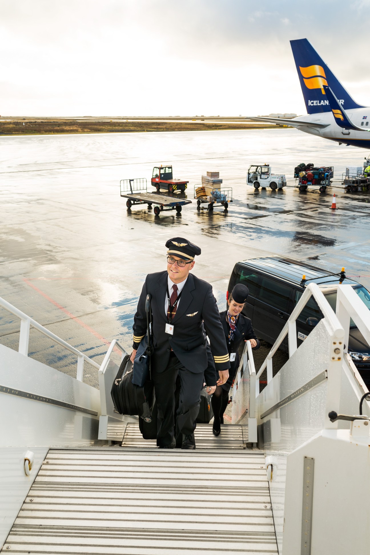 Icelandair pilot and flight attendant boarding aircraft on wet tarmac at Keflavík.