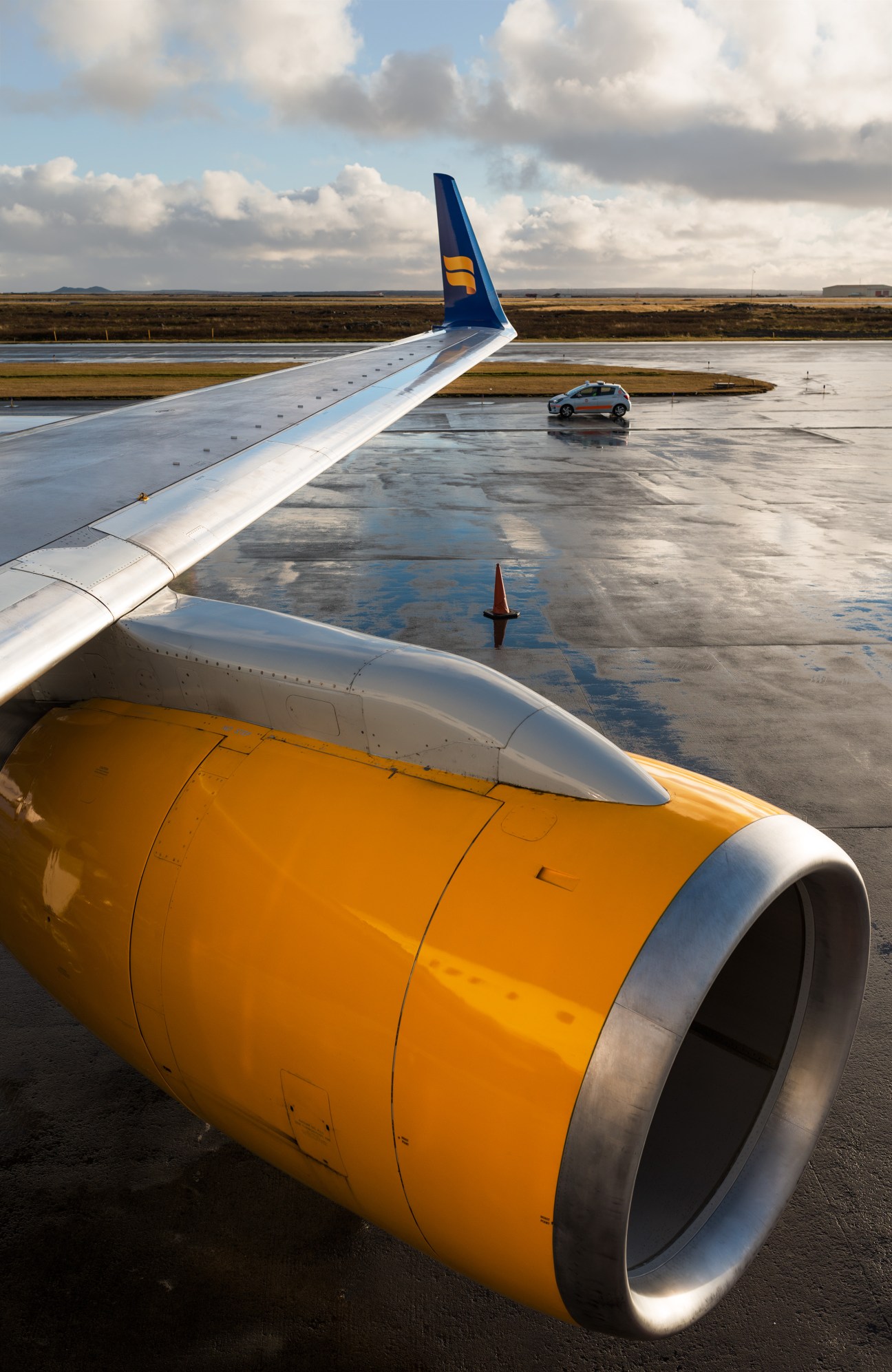 Icelandair Boeing 757 on tarmac at Keflavík International Airport with distinctive blue tail and yellow engine.