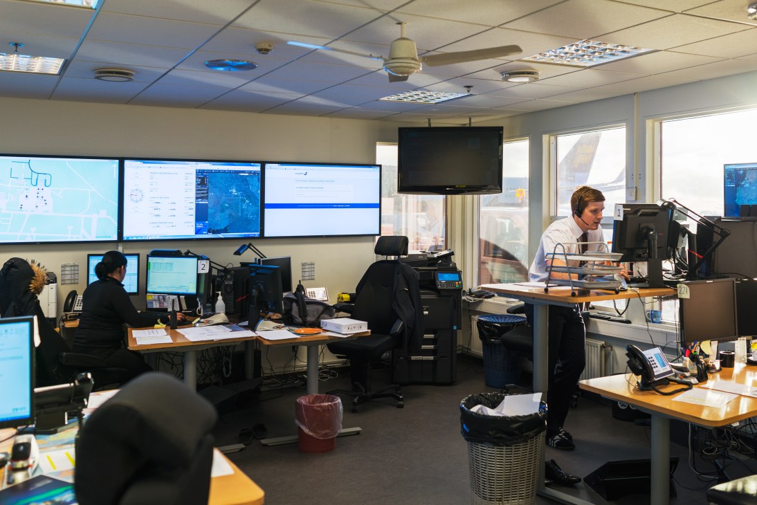 Staff working at computer stations in Icelandair Ground Operations Centre control room with multiple monitors displaying flight data.