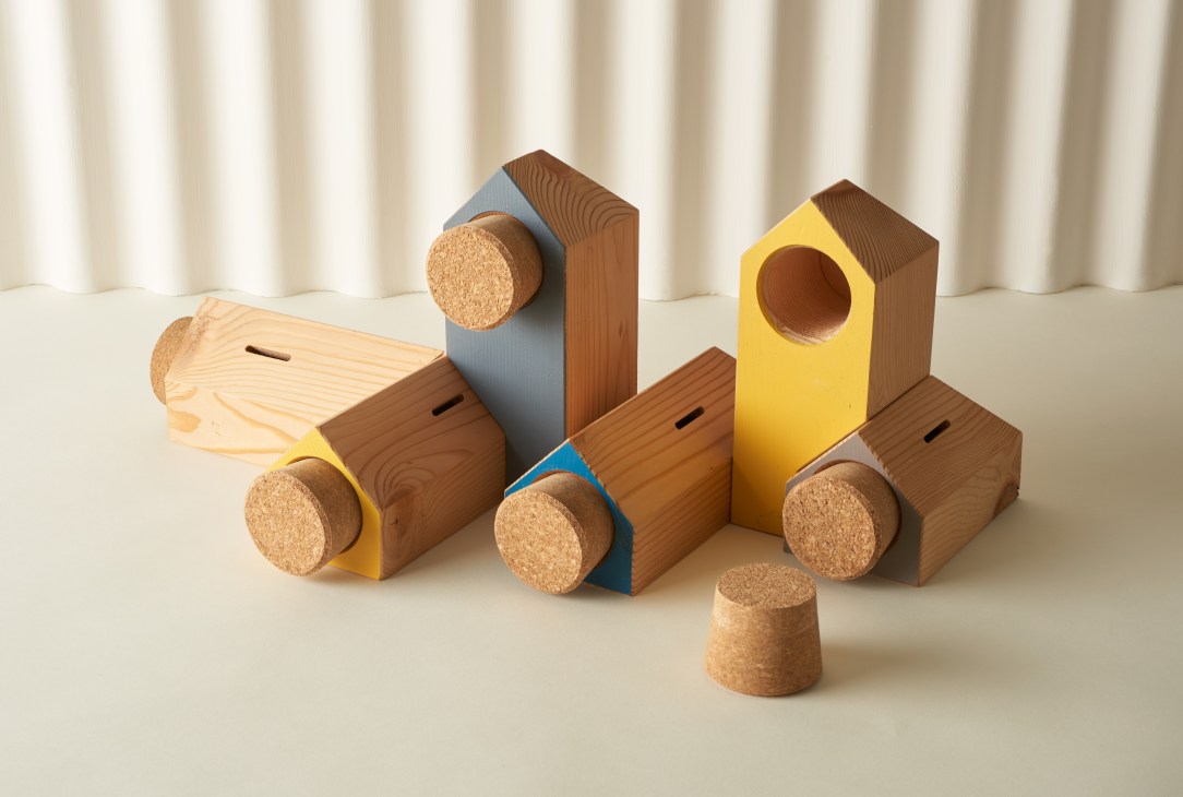 Colorful wooden money boxes by Noddy Boffin in various shapes and sizes with cork bases.