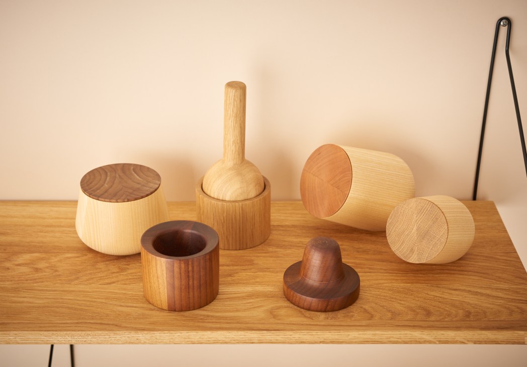 Wooden kitchen accessories by Shibui including storage containers, a nutcracker and pestle and mortar arranged on a wooden table.
