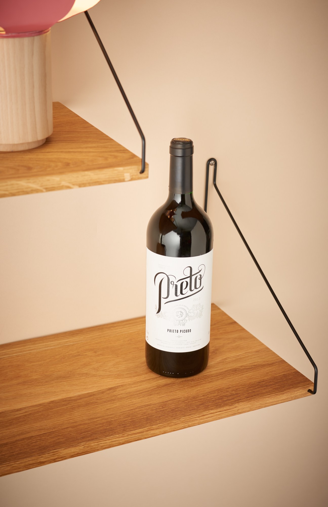 Bottle of Prieto wine on wooden shelving with minimalist styling.