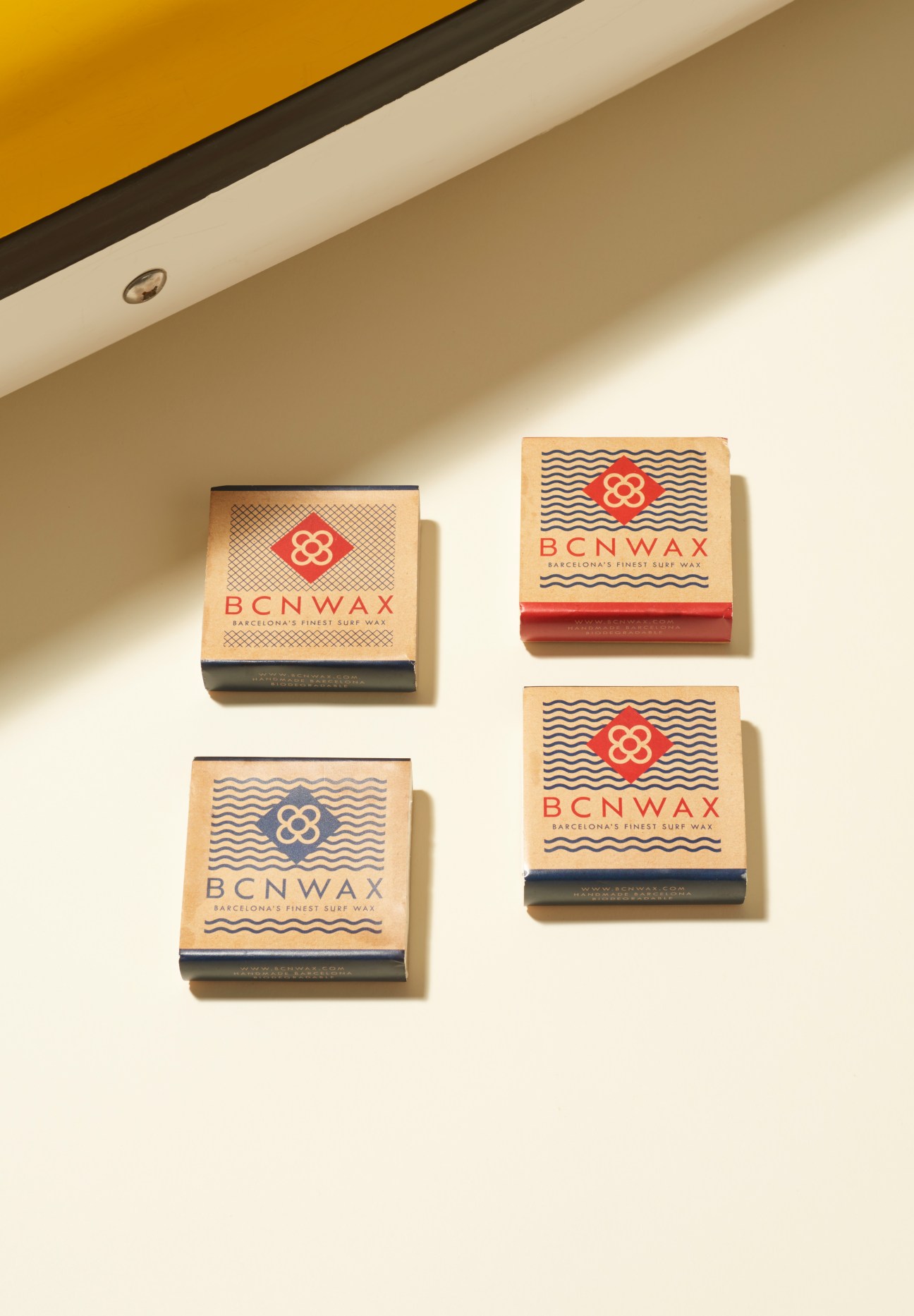 Three BCN Wax surfboard wax packages with nautical-inspired designs on a cream background.