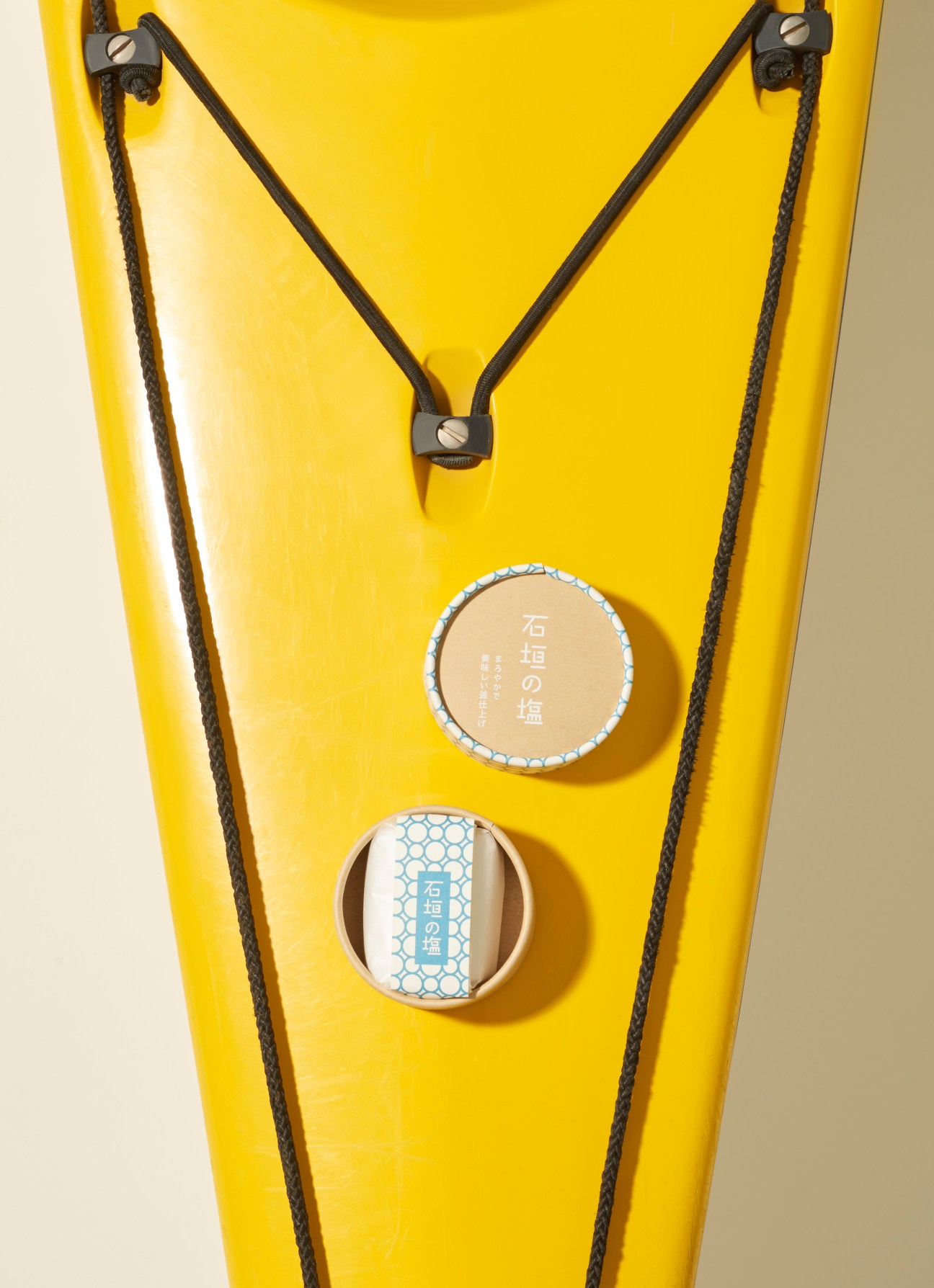 Salt containers with textured packaging displayed on yellow background by Idea N Design.