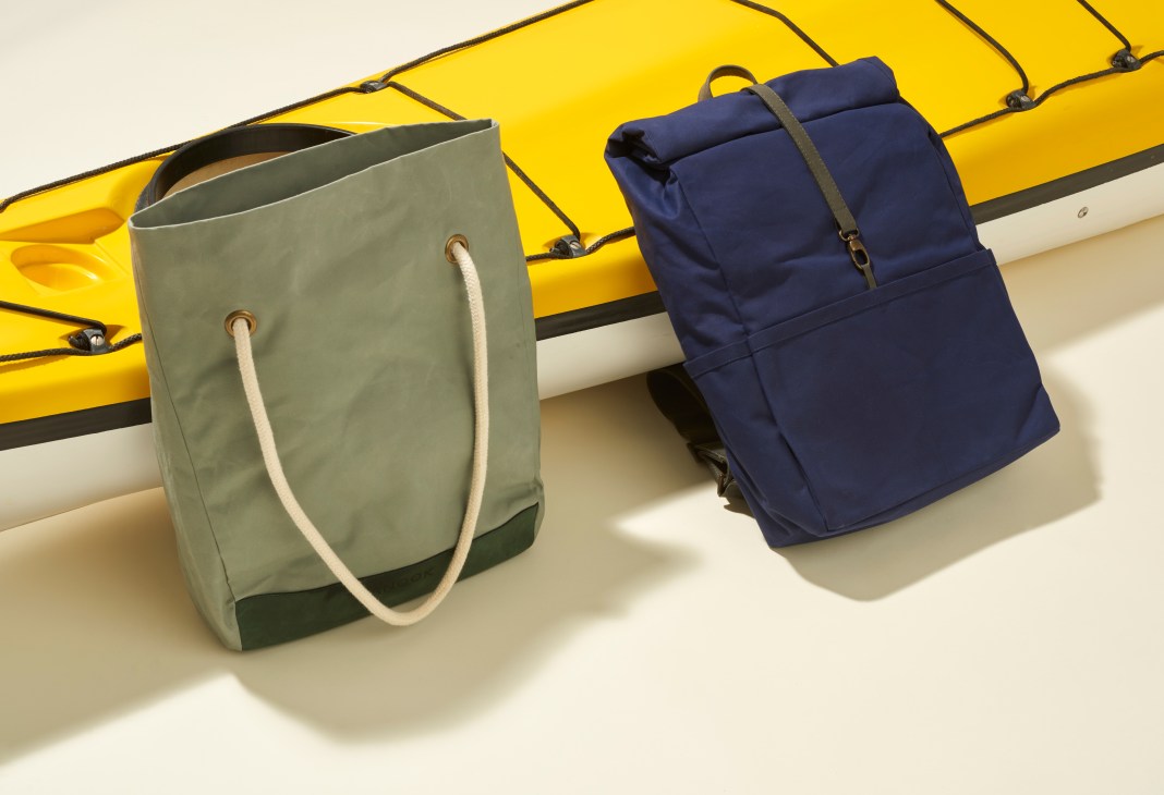Vanook leather and cotton bags in sage green and navy blue displayed against a yellow kayak.