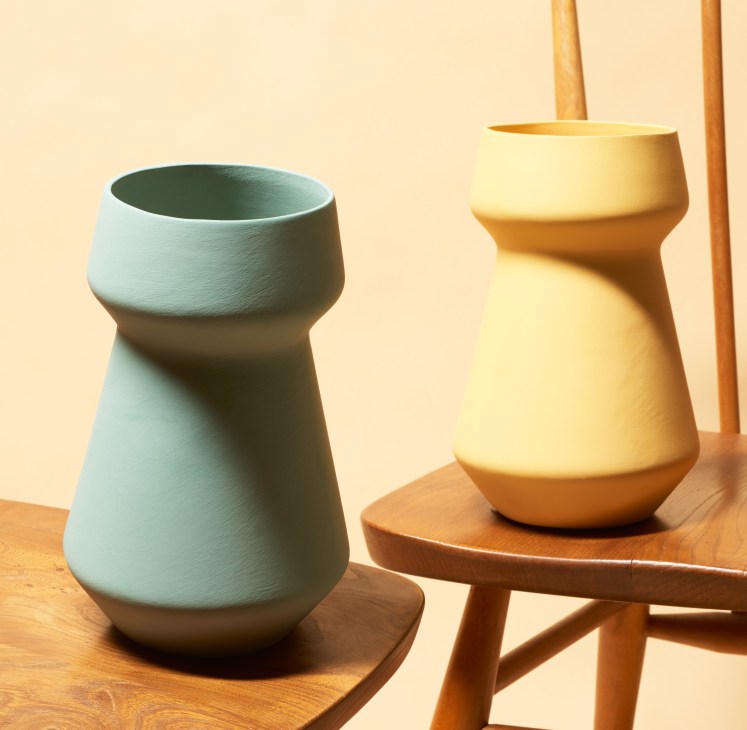 Two pastel-colored ceramic vases by Yahalomis displayed on wooden surfaces.
