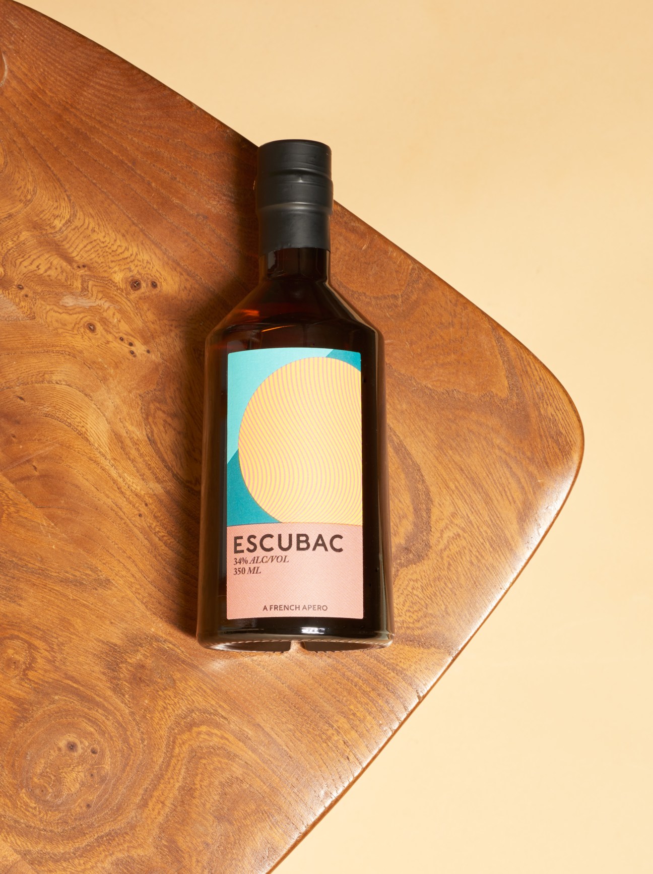Escubac spirit bottle by Sweetdram on wooden surface against cream background.