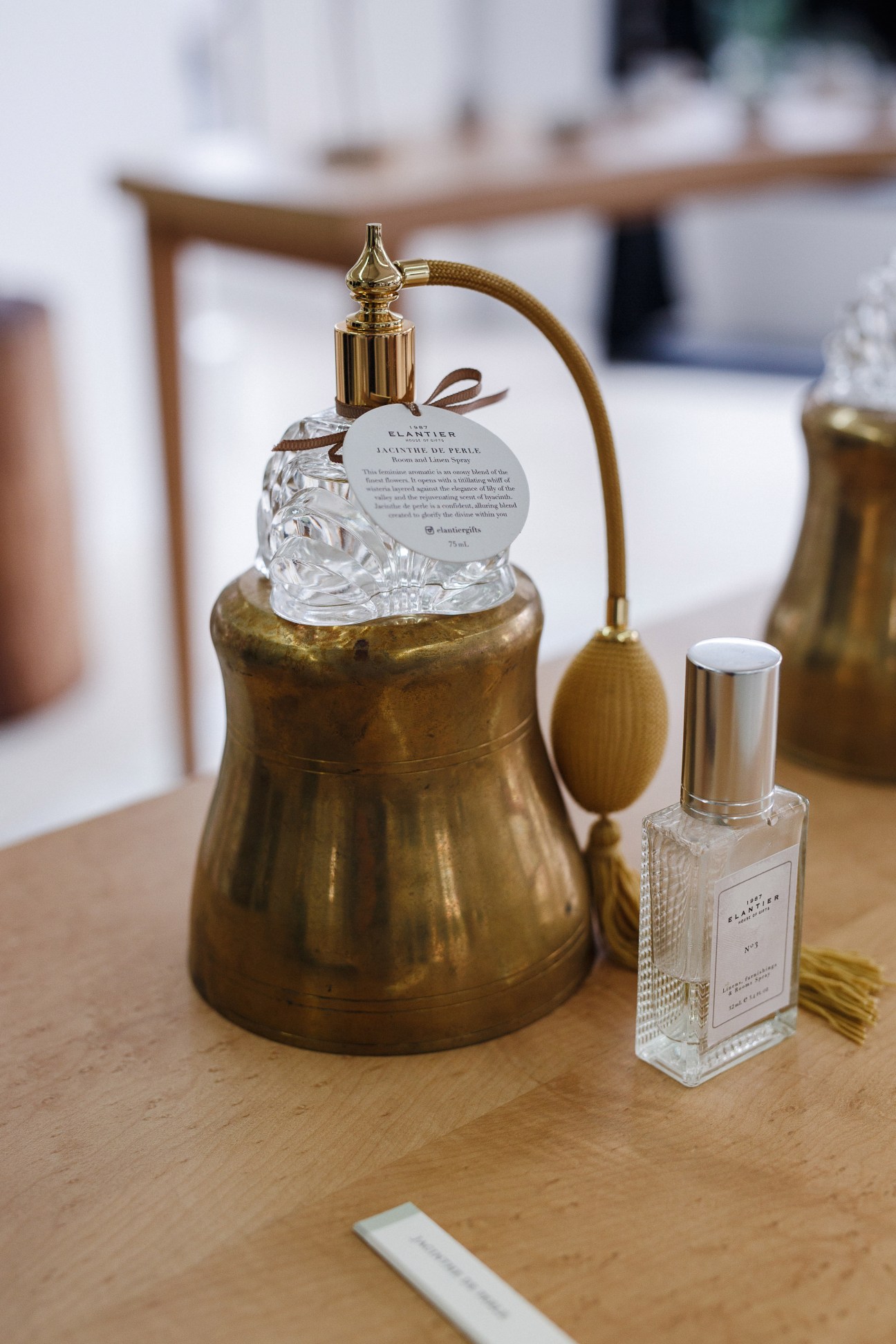 Luxury perfume bottles displayed on a wooden surface, featuring crystal and brass atomizers with product labels.