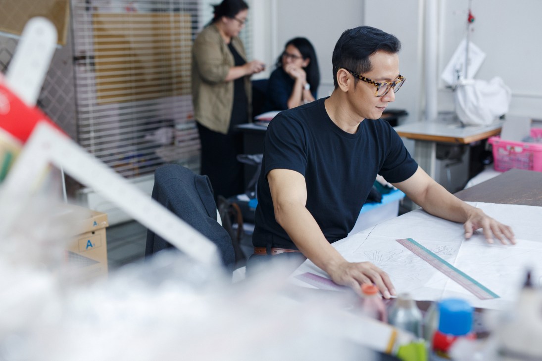 Designer working at a desk in Ara's minimalist showroom space with colleagues in the background.