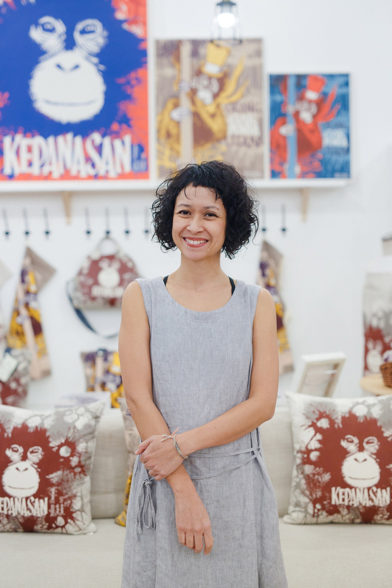 Melissa Sunjaya, founder of Tulisan textile brand, standing in her Jakarta boutique surrounded by colorful printed cushions and textile designs.