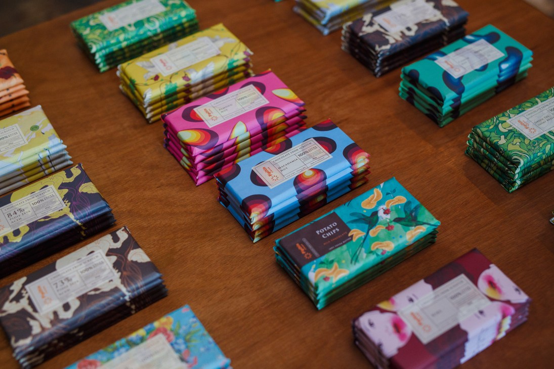 Colorful artisan chocolate bars from Pipiltin Cocoa displayed on a wooden surface, showing various flavors with vibrant packaging designs.