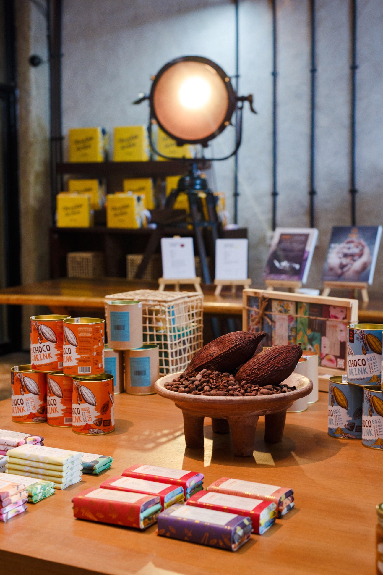 Pipiltin Cocoa's artisan chocolate products and cocoa beans displayed on wooden table with branded packaging and merchandise.