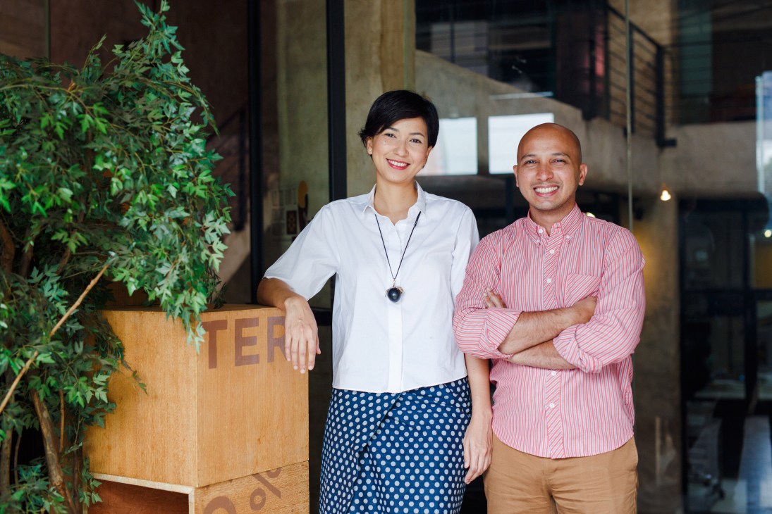 Two smiling entrepreneurs pose together at Pipiltin Cocoa with a potted plant beside them.