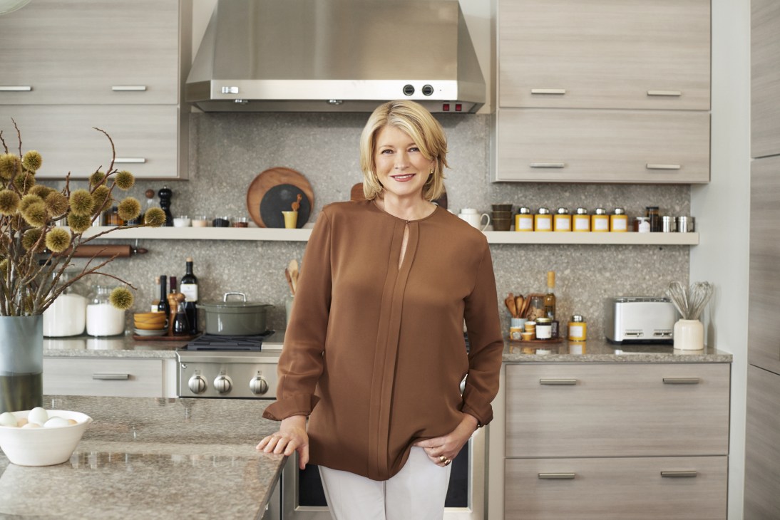 Martha Stewart standing in a modern kitchen wearing a brown cardigan.