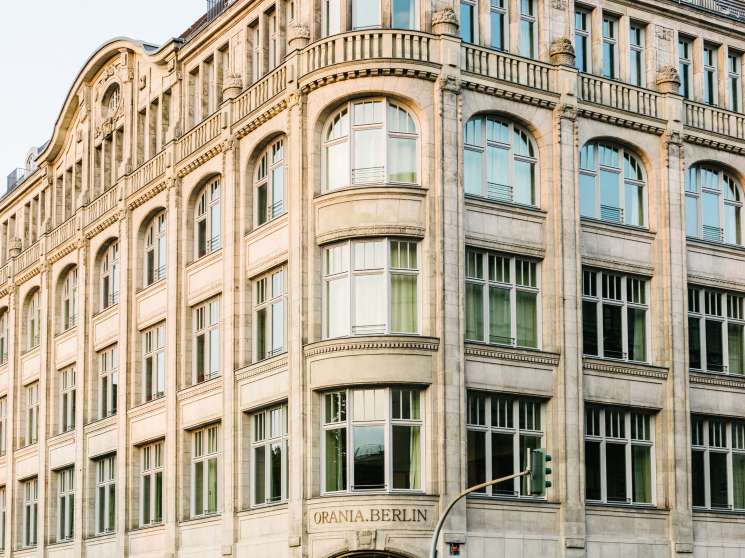 Orania Berlin's historic 1913 building on Oranienplatz with ornate stone facade and mansard roof.