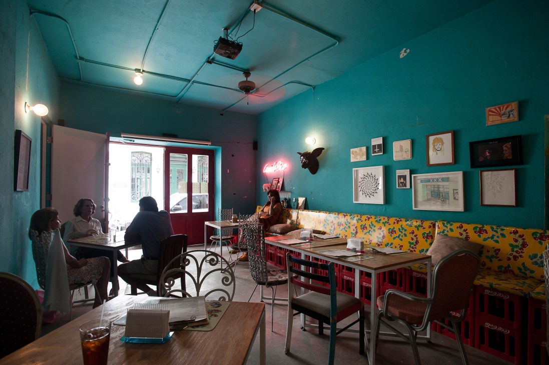 Diablo Rosso café interior with turquoise walls, vibrant artwork, and patrons seated at tables.