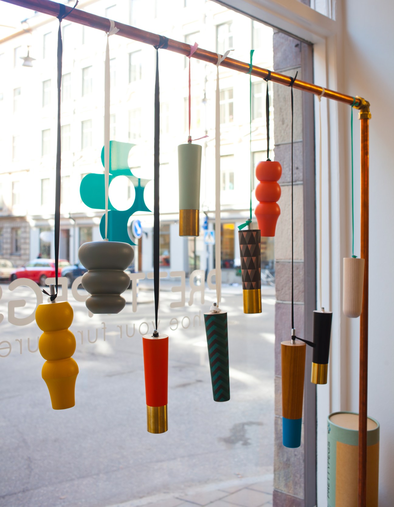 Colorful hanging decorative pegs and wooden accessories displayed in a bright shop window.