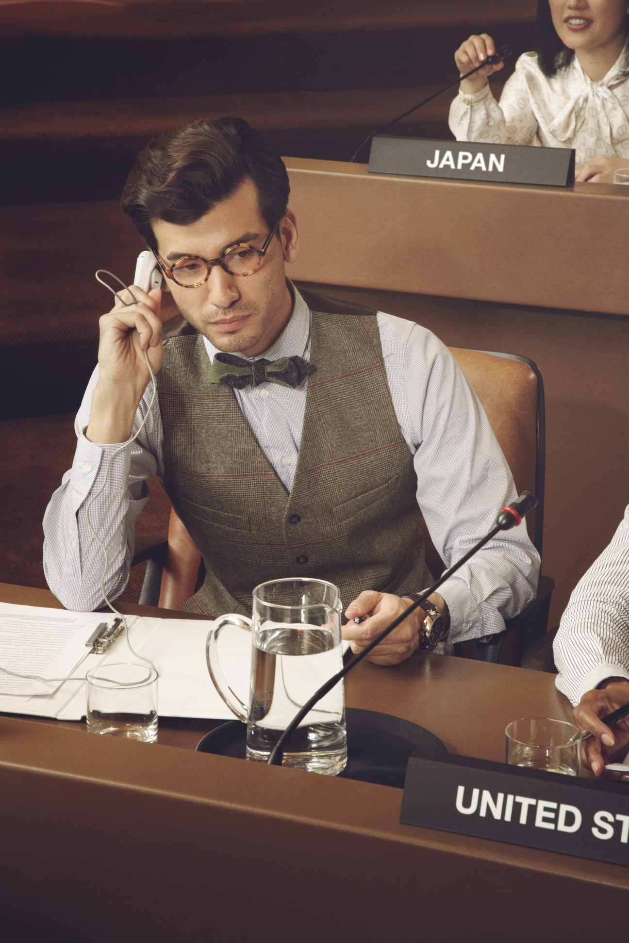 Male diplomat in tweed vest and bow tie at UN assembly desk labeled Japan.