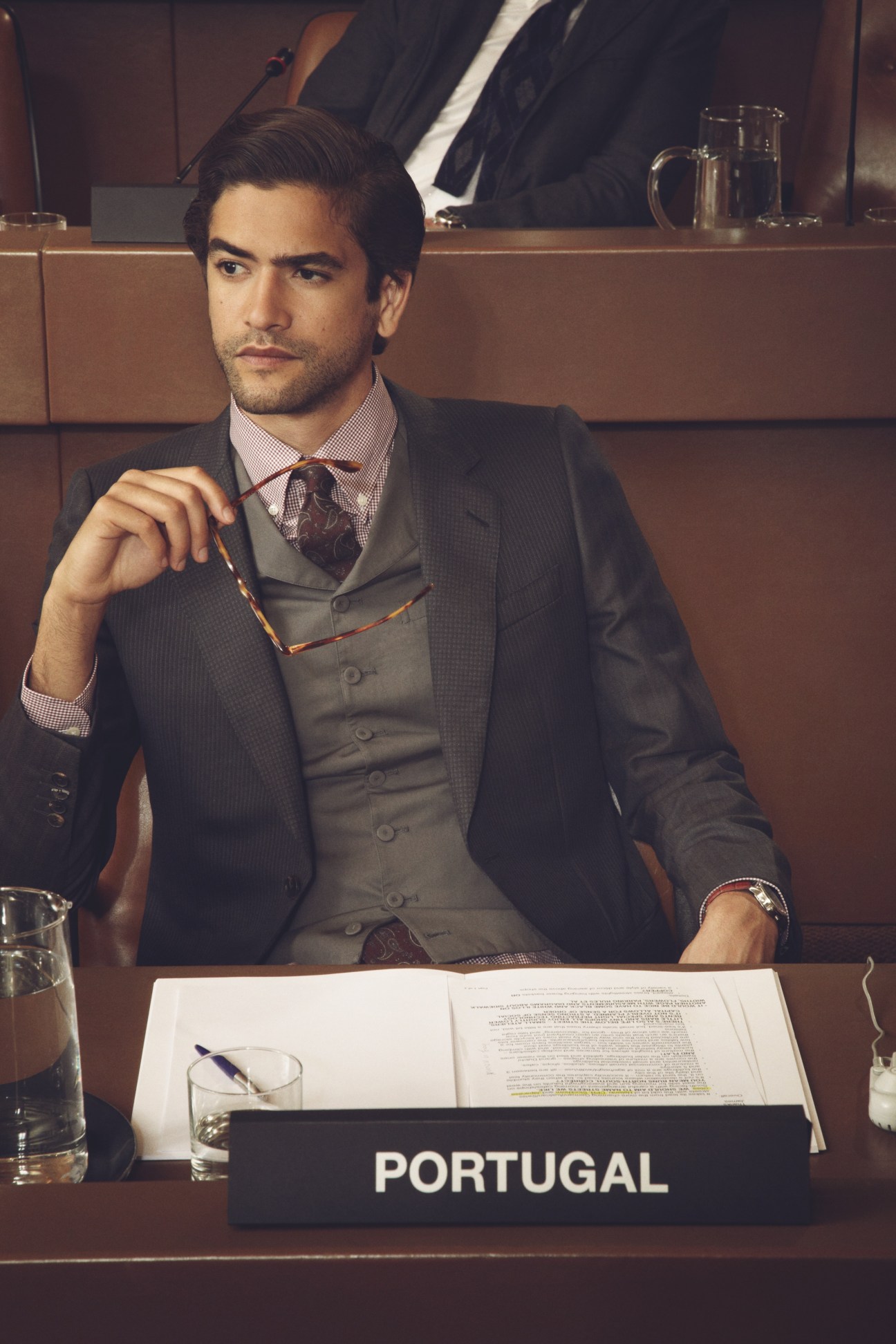 Male model in formal business attire seated at UN desk labeled Portugal.