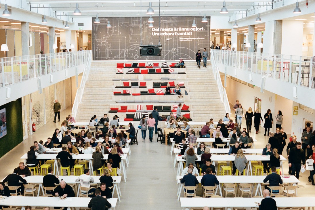 Overhead view of Ikea employees during fika break in a modern cafeteria with red and black modular seating on stairs.