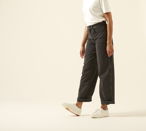 Model wearing high-rise straight leg jeans by Uniqlo in classic blue wash with white sneakers