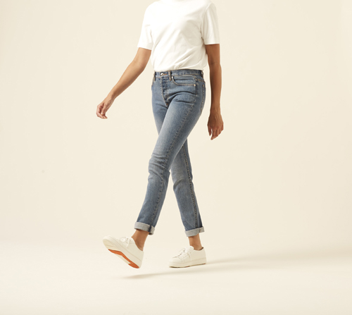 Woman wearing APC Petit new standard jeans in slim fit dark indigo with white t-shirt and white sneakers.