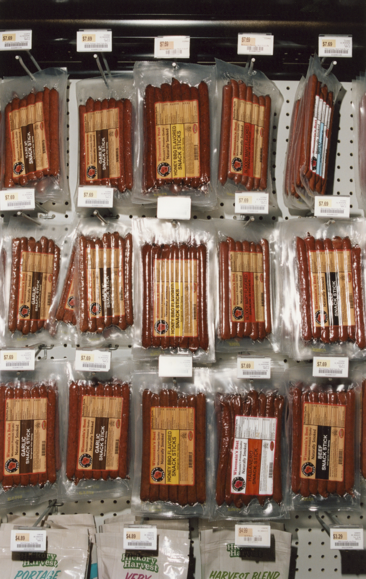 Packaged smoked meat and sausages displayed on retail shelves with price tags at a truckstop.