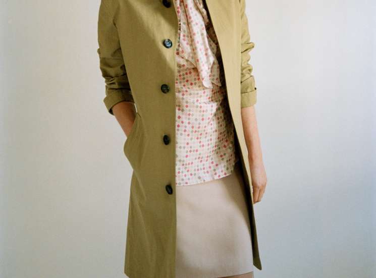Model wearing Burberry Prorsum coat, Kiton blouse, and Akris skirt against neutral background.