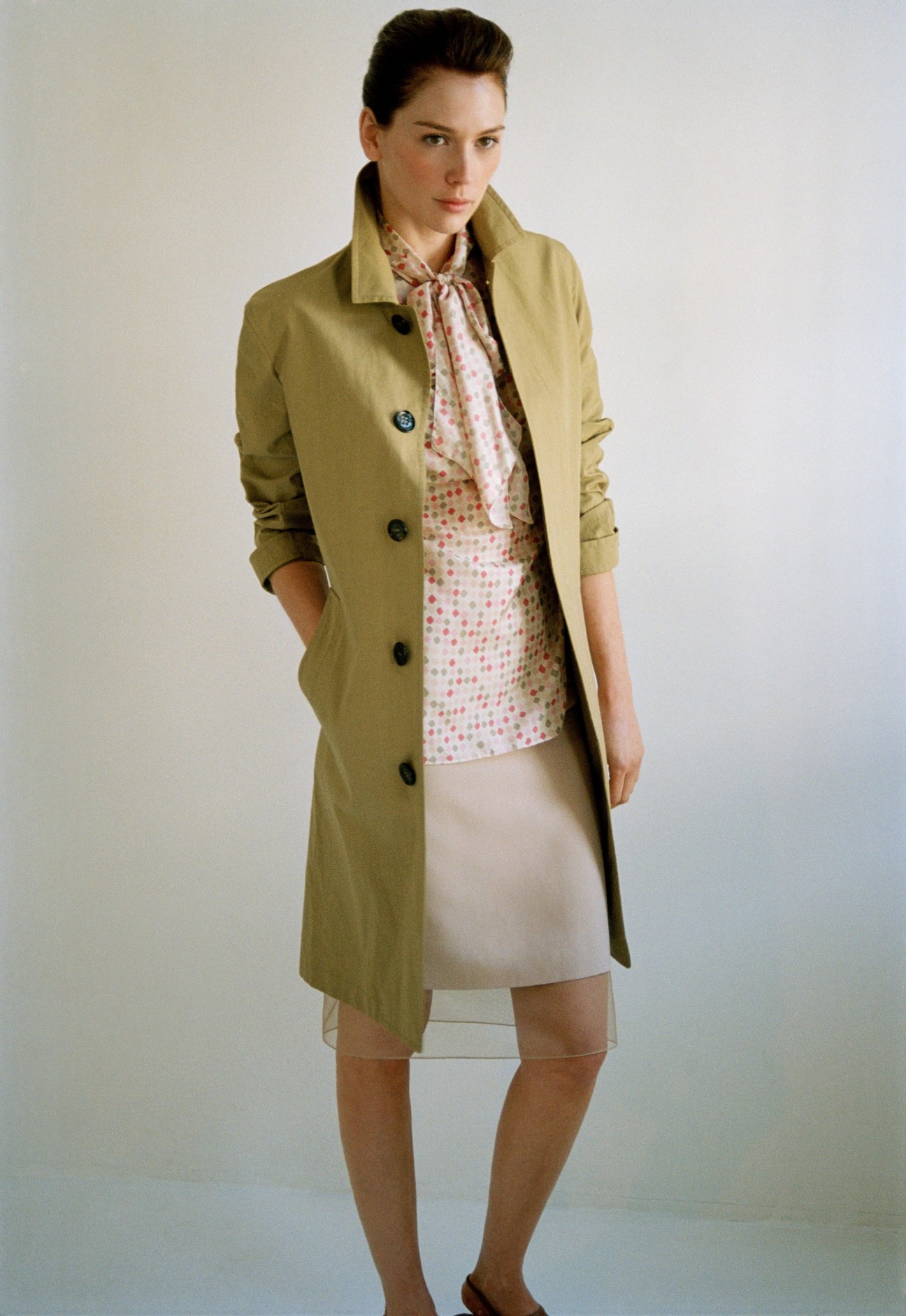 Model wearing Burberry Prorsum coat, Kiton blouse, and Akris skirt against neutral background.