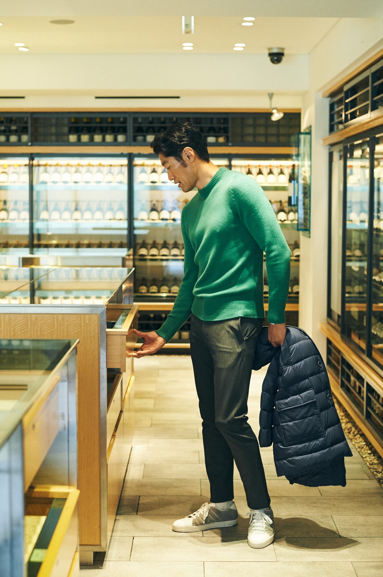 Man in green Bottega Veneta jumper and dark coat shopping in a Japanese delicatessen.