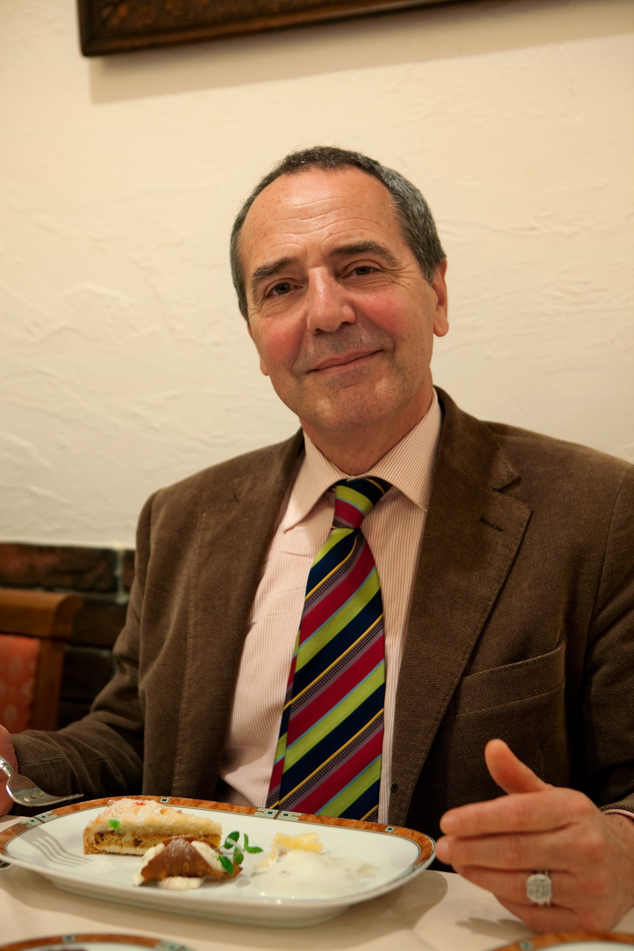 Bruno Contigiani, founder of the Art of Slow Living movement, seated at a dining table with a plate of food.