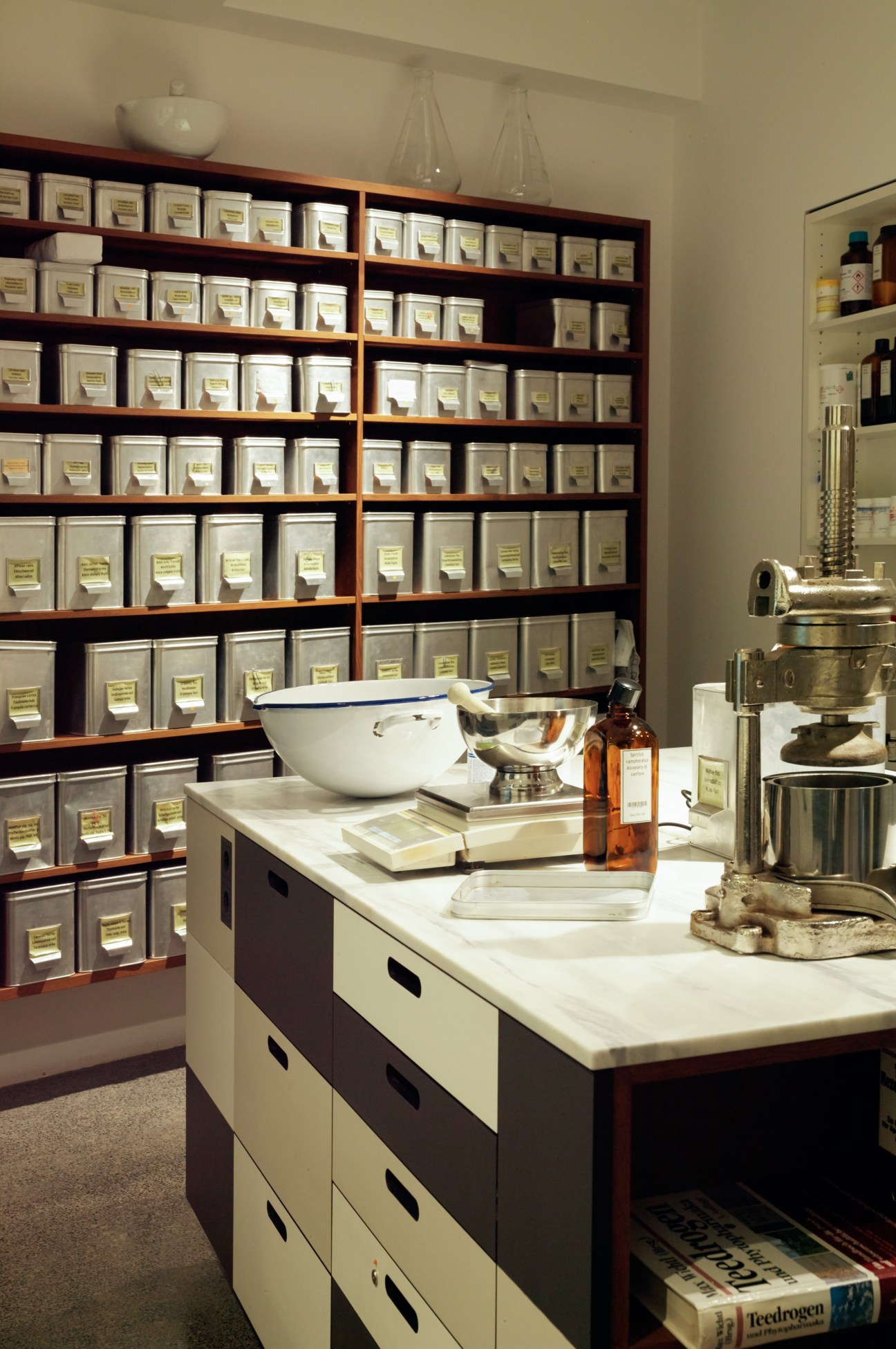 Wooden shelving system filled with white containers and laboratory equipment in a pharmacy workspace