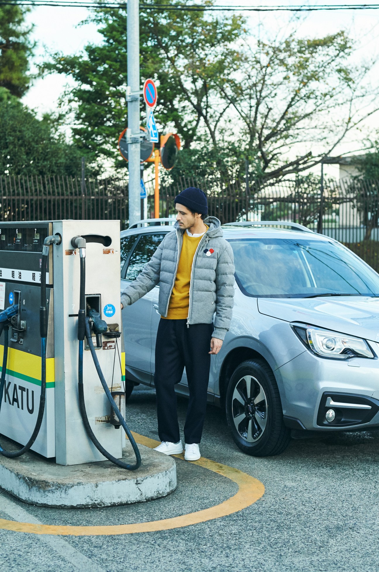Man in winter coat filling up Subaru Forester at gas station in Japan