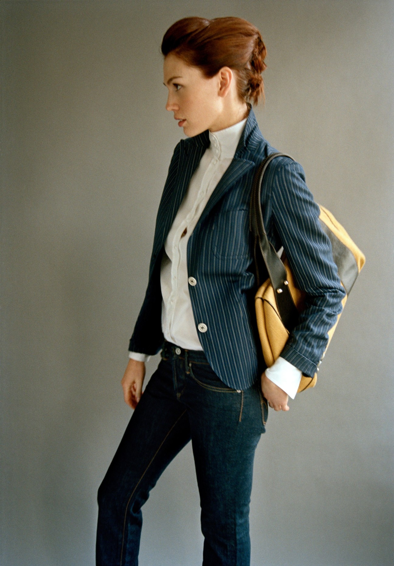 Woman wearing pinstriped jacket by Montedoro, white shirt, jeans, and yellow Missoni bag.