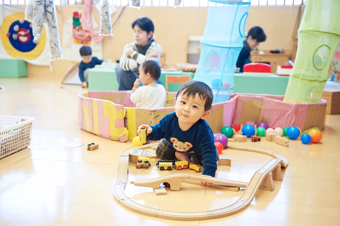 Toddler plays with wooden train set at Kana-chie child support centre in Yokohama.