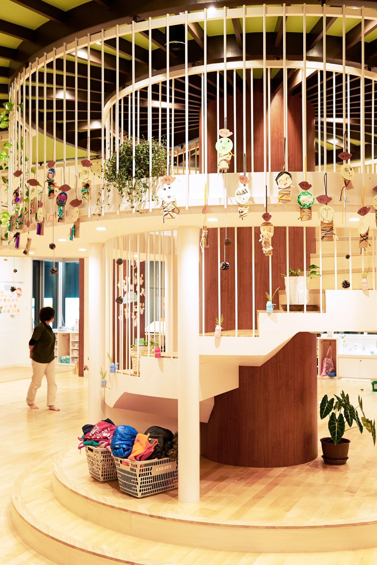 Interior of P's Smile nursery showing a spiral staircase with wooden railings, hanging children's artwork, and a bright, modern play space.
