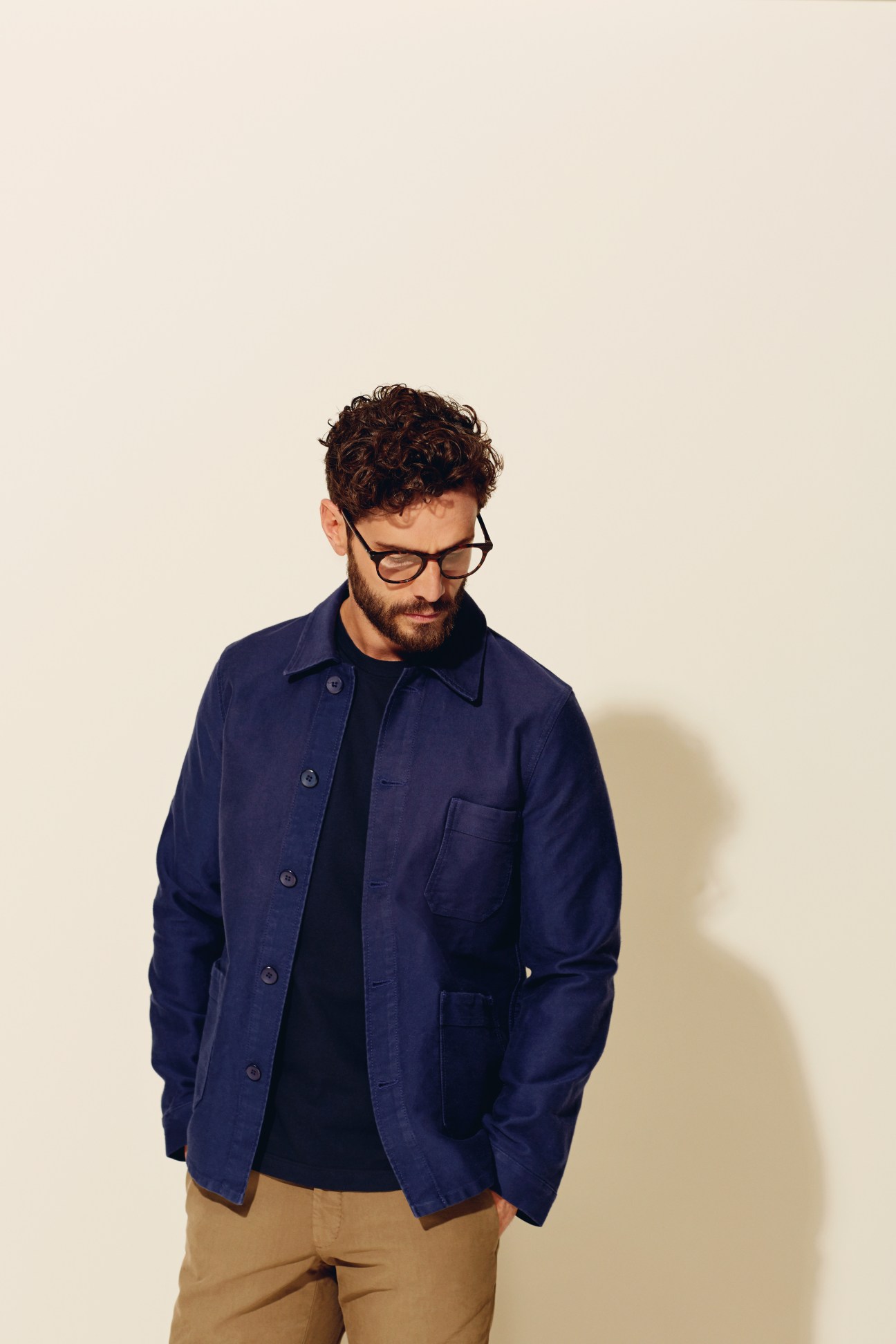 Man wearing Le Mont Saint Michel navy work jacket with black shirt and tan trousers.
