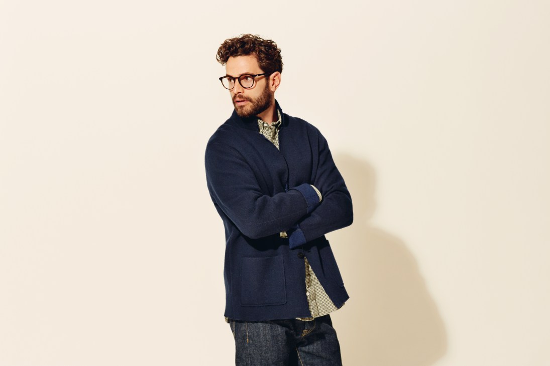 Man wearing dark navy reversible cashmere jacket over checkered shirt with glasses.