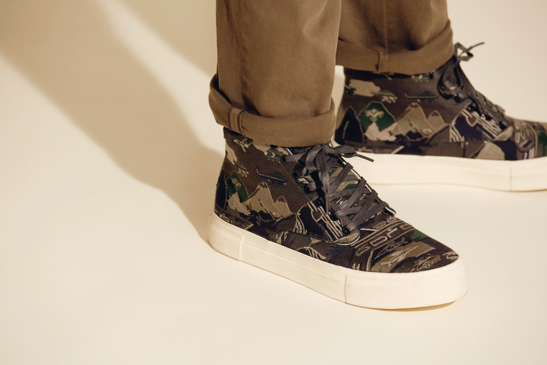 Eytys patterned high-top sneakers with white sole worn with tan trousers.