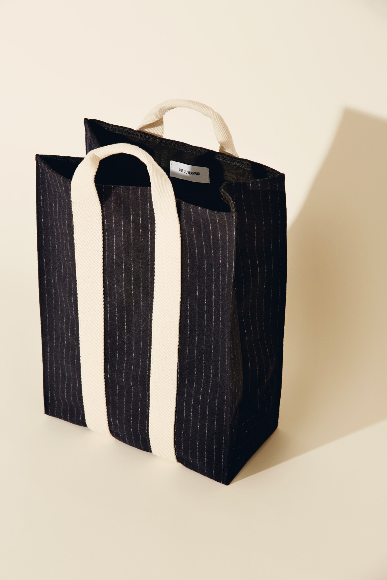 Black pinstriped tote bag with cream-colored handles by Rue de Verneuil