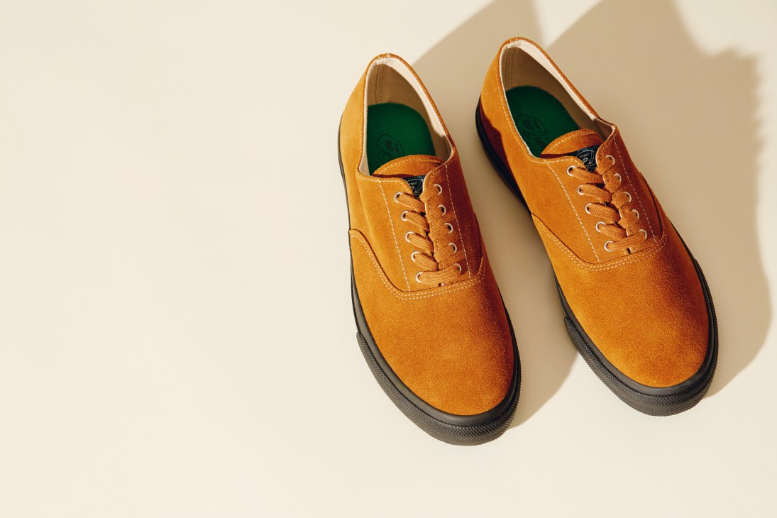 Pair of Sperry x YMC orange suede boat shoes with dark soles and green insoles, displayed on a neutral background.