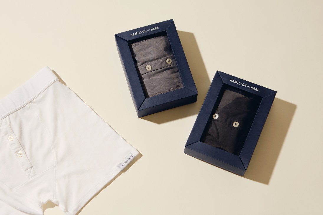 Hamilton and Hare boxers displayed in navy packaging alongside a white folded pair on a cream background.