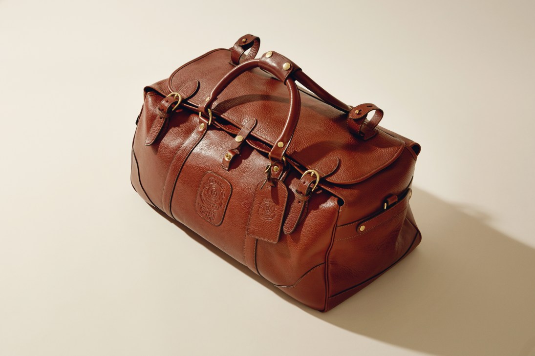 Cognac leather Ghurka Kilburn bag with brass accents and detachable shoulder strap.