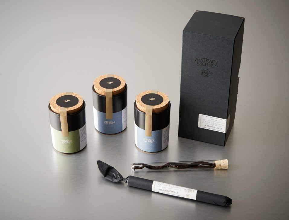 Pfeffersack und Soehne spice canisters with cork lids and a black box, displayed with a scoop and small bag.