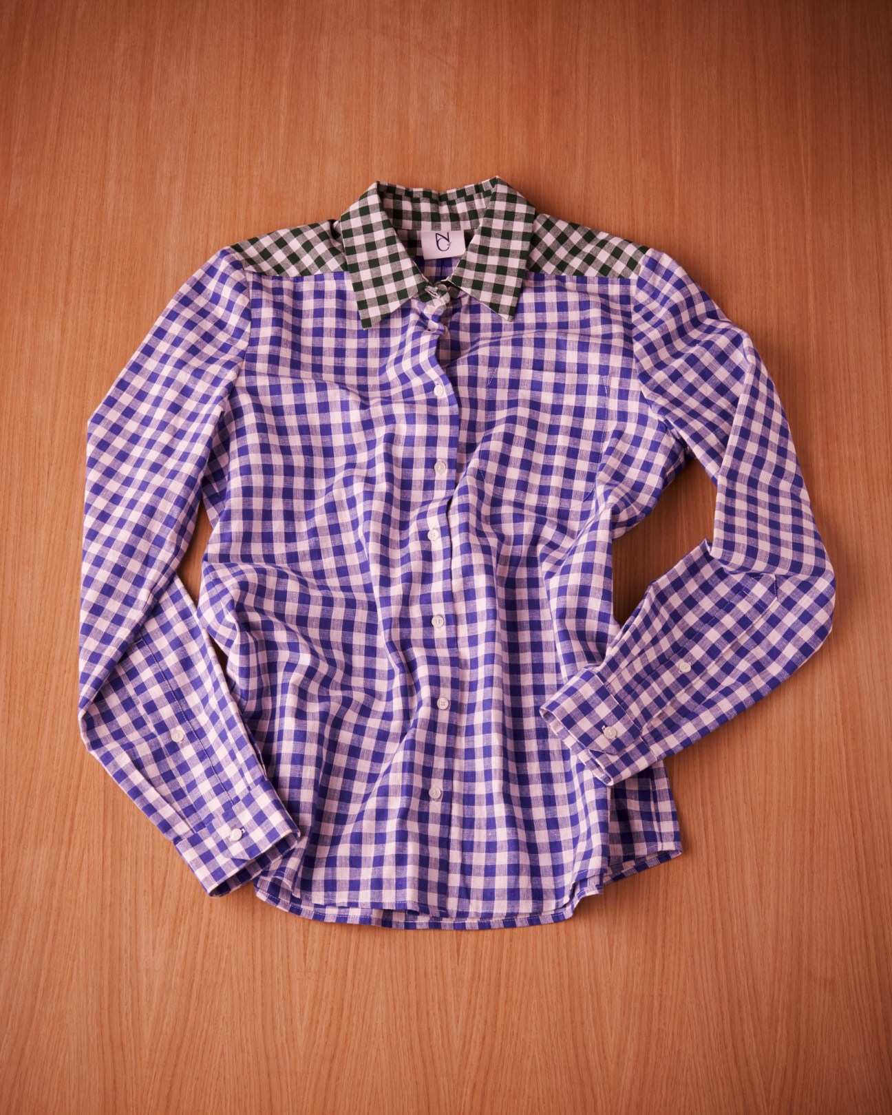 Natures of Conflict purple and white checked cotton A-line shirt on wooden background.