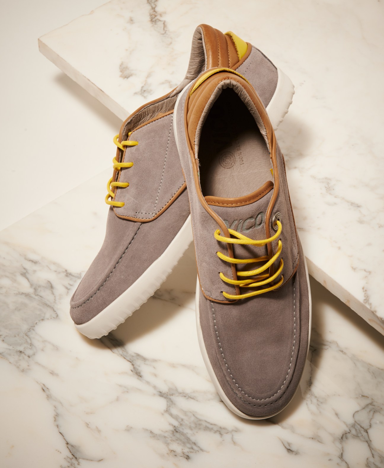 Vico Glebe shoes in grey suede with yellow laces and tan leather trim on marble background.