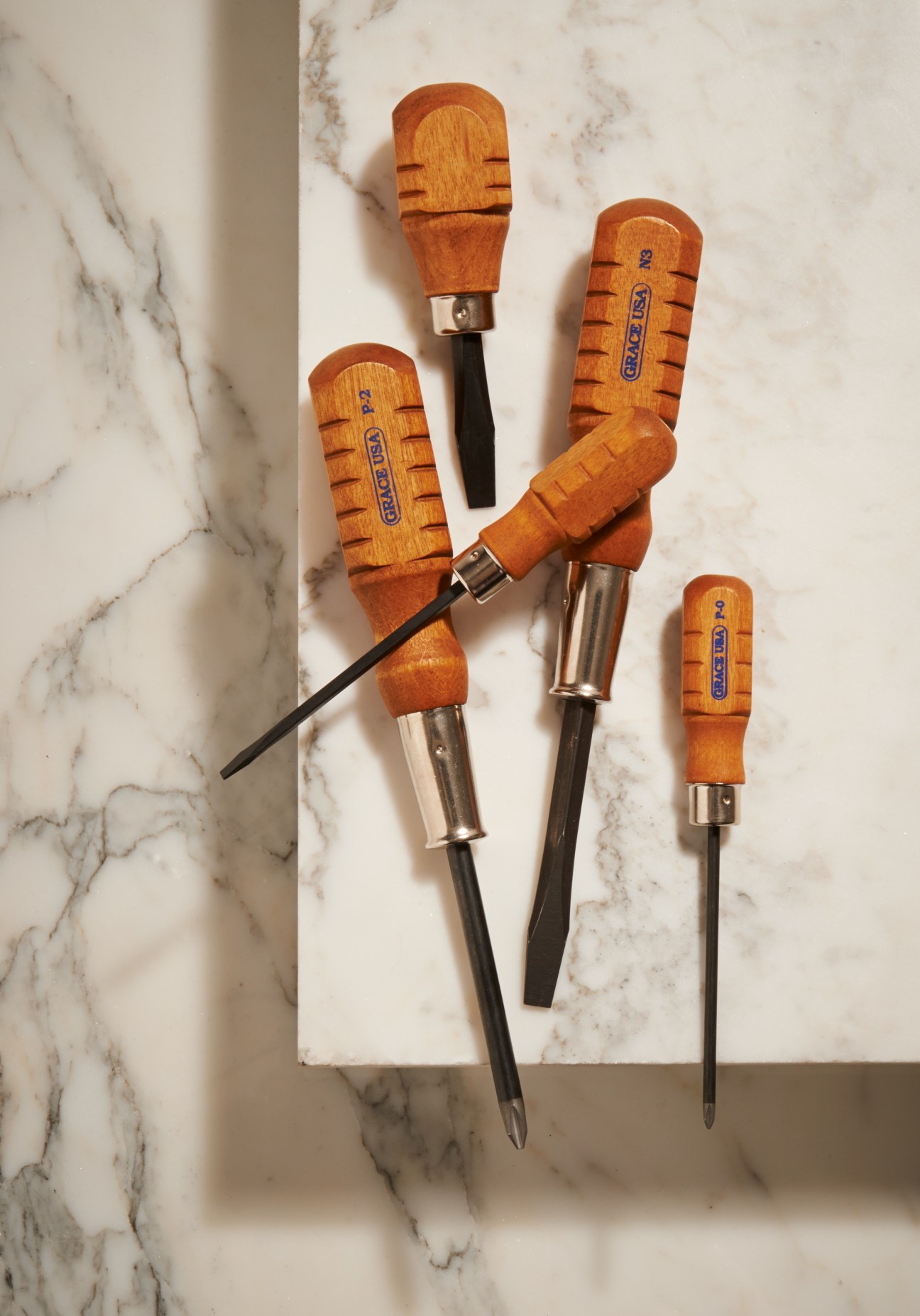 Grace USA chromium/vanadium screwdriver set with wooden handles arranged on marble surface.