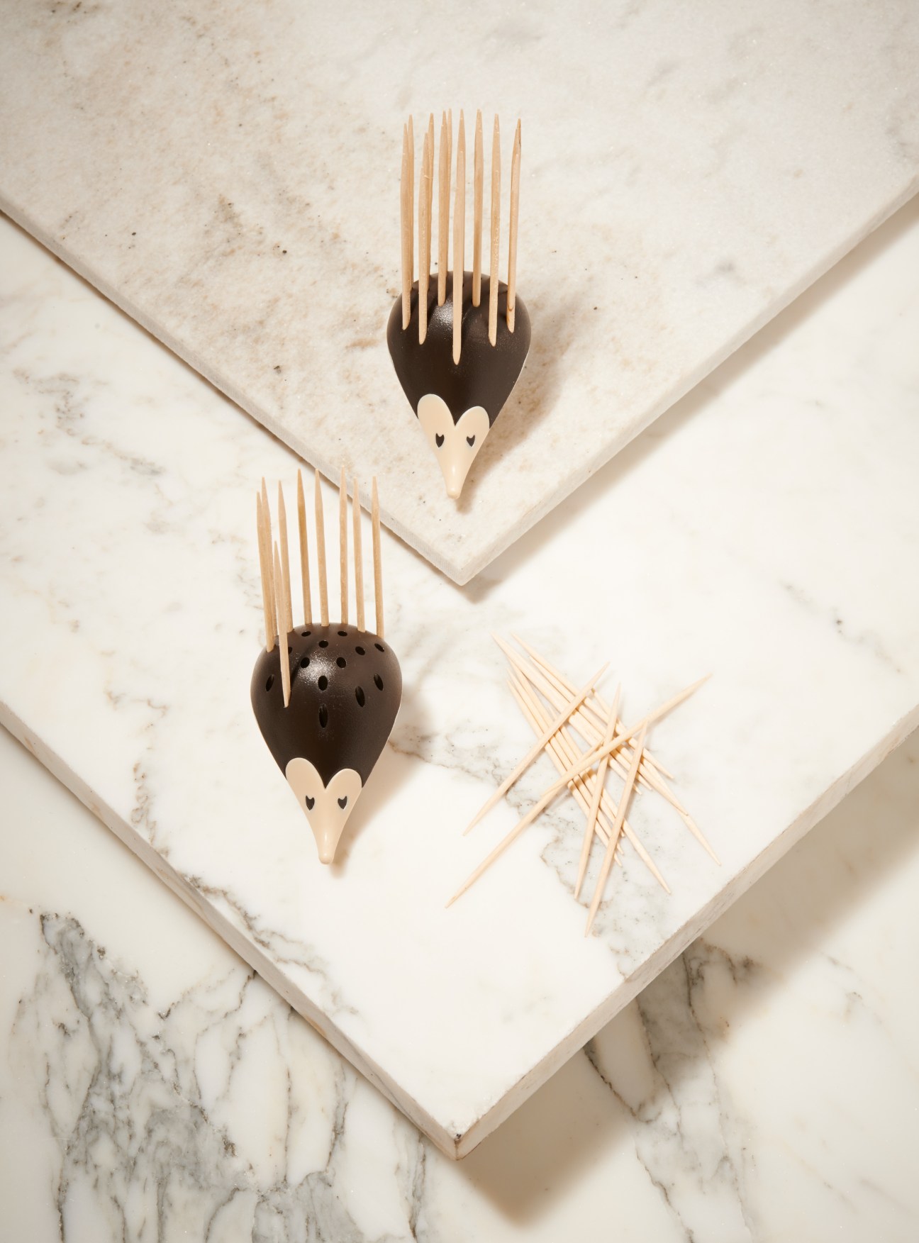 Kipik hedgehog toothpick holders with wooden picks on marble surface.